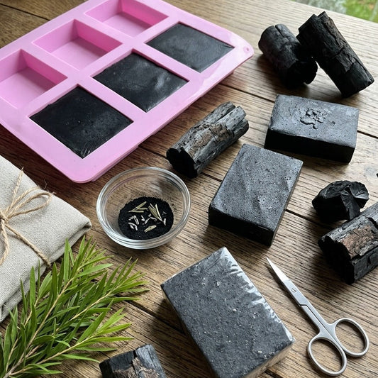 Elixoria Herbs handmade charcoal soap in a rectangular shape with a rich black, charcoal-speckled texture, displayed in a premium botanical setting for natural skincare.